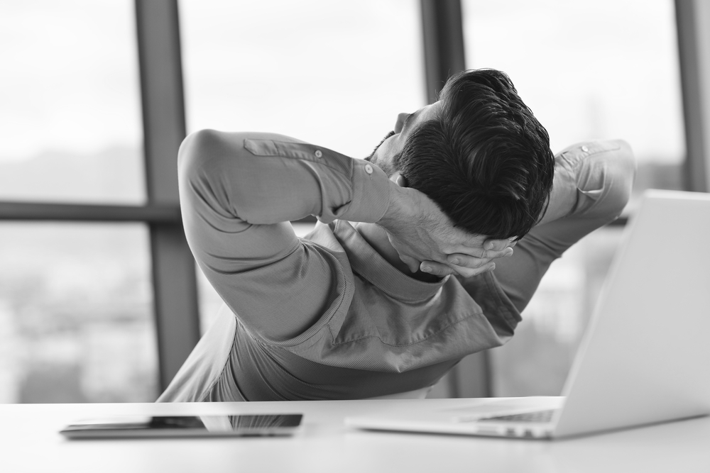 Man reclining at desk with laptop