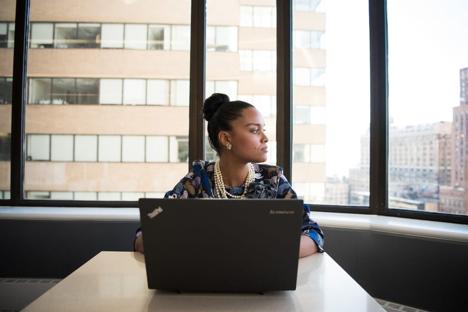 woman staring out window in front of laptop